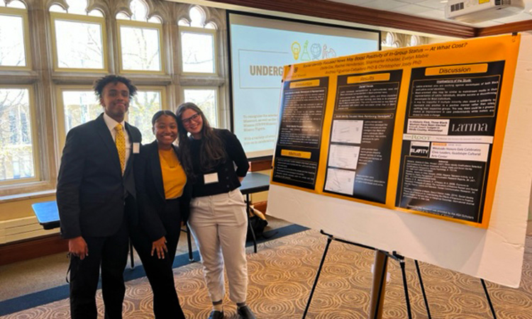 A group of students posing for a picture by their research poster.