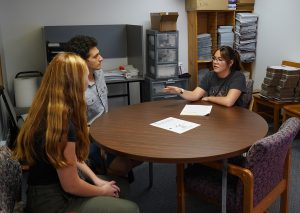 A group of students sitting around a table talking with each other.