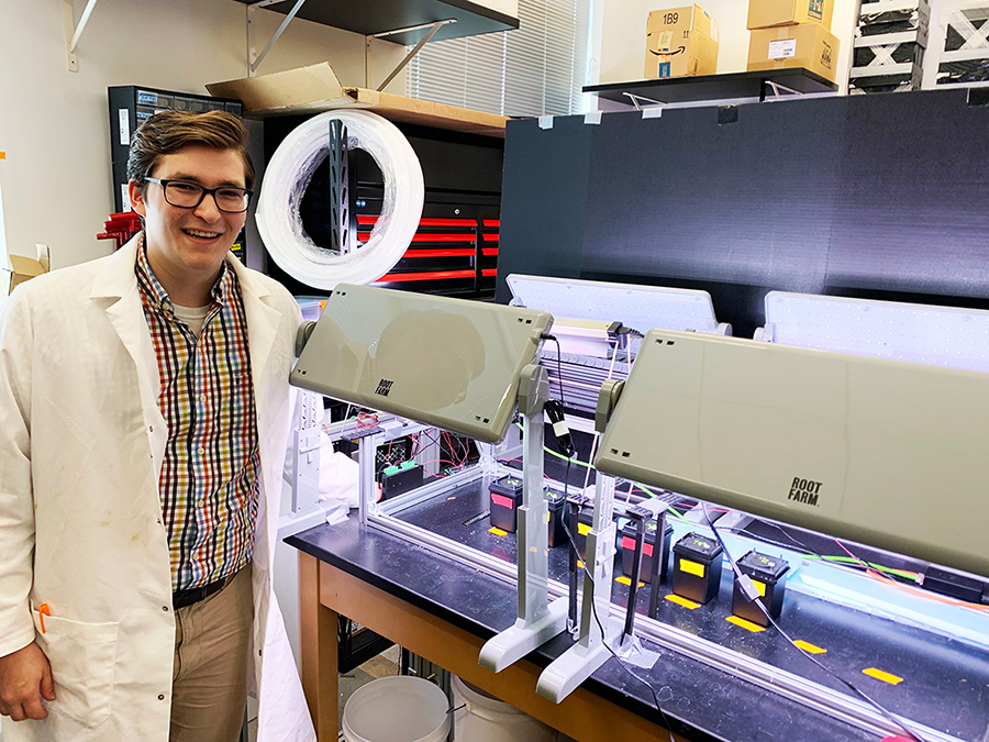 Landon Swartz posing for a photo in front a piece of research equipment.