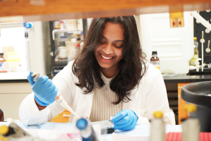 Anvitha Boosani, in a lab coat, performing a research task.