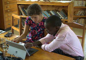 Two individuals looking at a laptop conducting a research task.