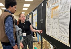 A student showing their research via a poster presentation.