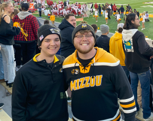 Two students smiling for the camera while at a football game.