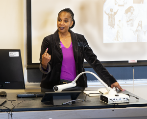 Maya Gibson standing at a desk, talking to her classroom full of students.