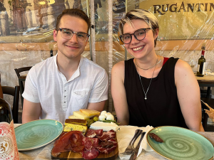 Two individuals smile for the camera before eating a meal.