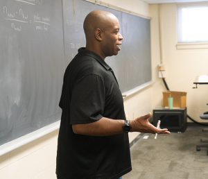 Reginald Rogers teaching to a classroom full of students.