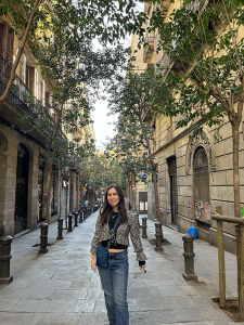 Sara George posing for a picture surrounded by building an trees.