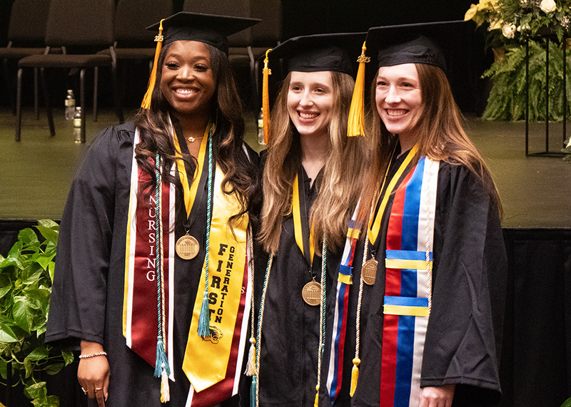 Students smiling during a graduation ceremony.