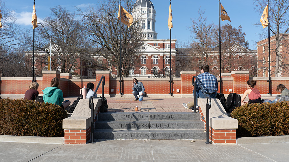 A group of students listening to a professor while in front of Jesse Hall.