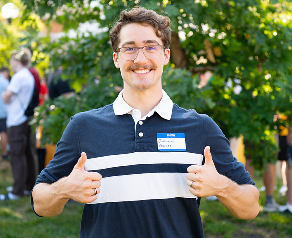 A student smiling while giving thumbs up to the camera.