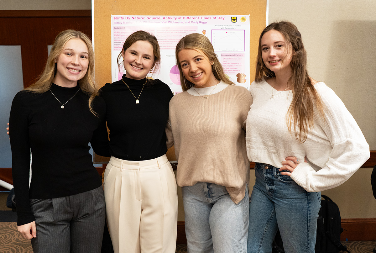 A group of four students smiling while posing for a picture together.