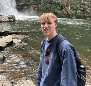 Dane Walker smiling while posing for a picture in front of a waterfall.