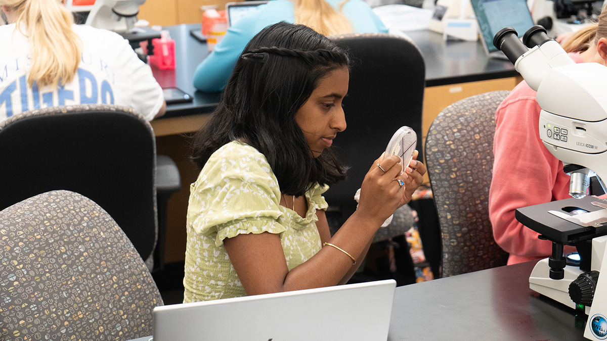 Manisha Muthukaruppan studies a slide during class.