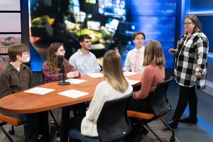 Amy Simons talking to a group of students who are sitting around a table.