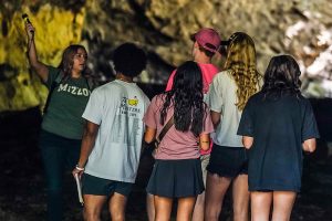 Students and a professor looking around inside a cave.