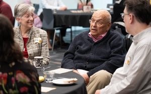 Bill Bondeson sitting at a table talking to a group of individuals.