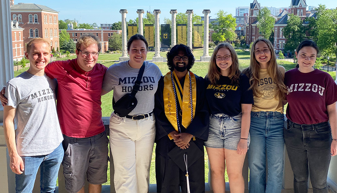 Students posing for a photo in front of the Mizzou columns.