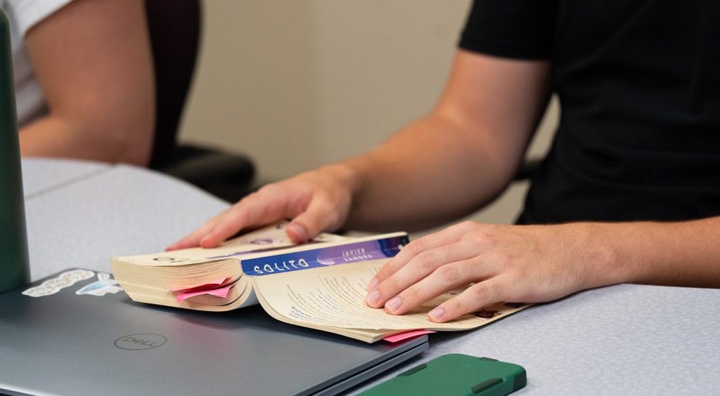 A picture of hands sitting on top of a book.