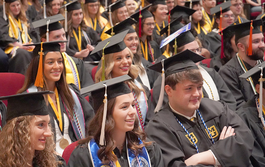 A group of students smiling in their graduation cap and gowns.