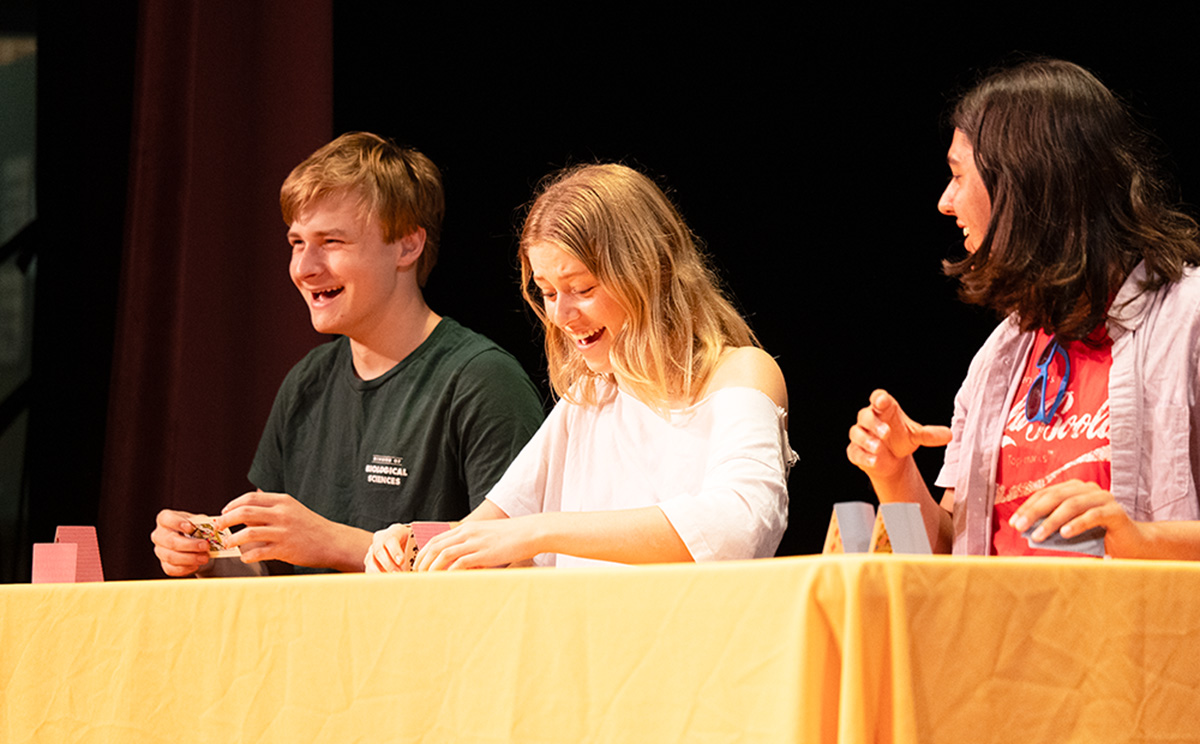 A group of laughing while trying to stack playing cards.