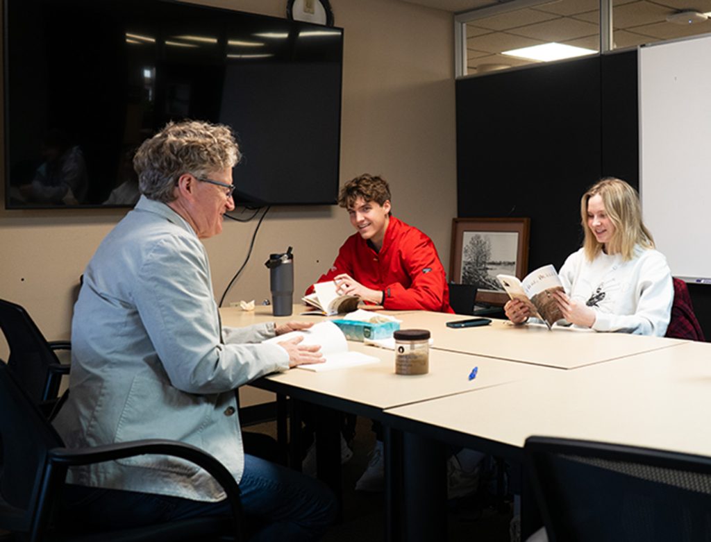 Two students smiling at their professor while the professor teaches.