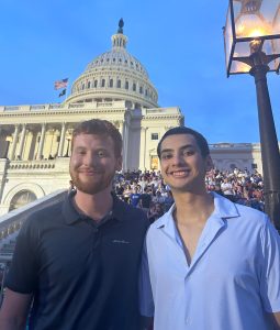 Two individuals smiling and posing for a picture in front of the White House.