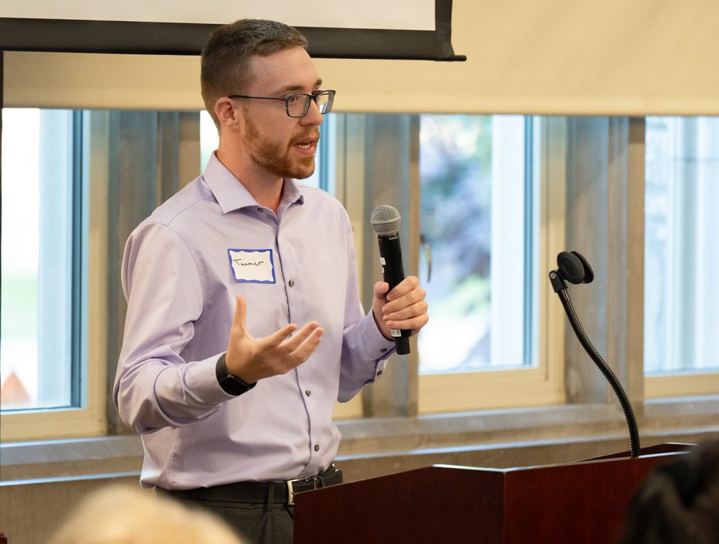 Tanner Smith holding a microphone while speaking to a crowd.