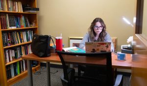 Jane Ray working on her laptop in a small office, that feature several books.