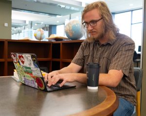 Graham George working on his laptop while sitting in the library.