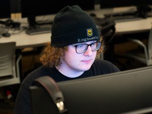Ashton Wooster sitting in a computer lab doing work on a computer.