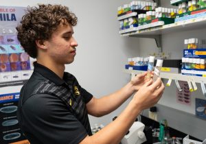 Zach Wright holding up two vials of liquid while in a laboratory.