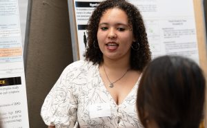 Nya Dodd discussing her research with another individual during her poster presentation.