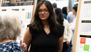 Pari Patel talking with another individual while presenting her research.