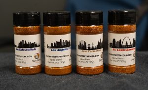 A group of four spice bottles sitting by each other.