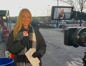 Charlotte Cicero smiling while holding a microphone, in preparation of doing a news broadcast.