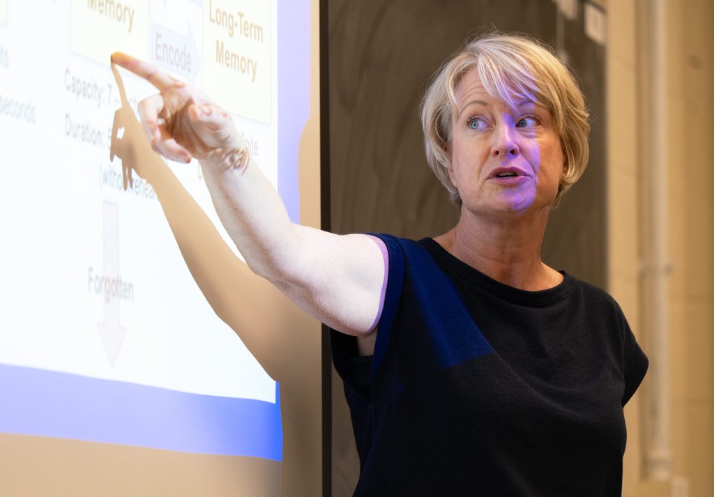 A professor pointing at a whiteboard while teaching.