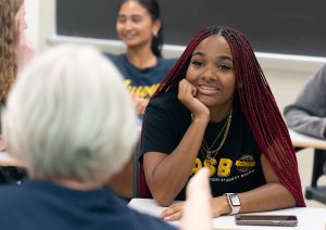 A student smiling while talking with a professor.
