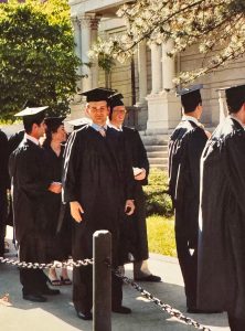 Brent Steele smiling and posing for a picture while wearing his graduate robes.