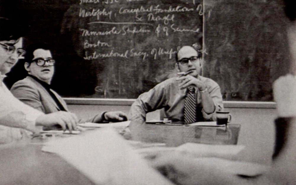 Bill Bondeson sitting at a table and talking with other individuals.