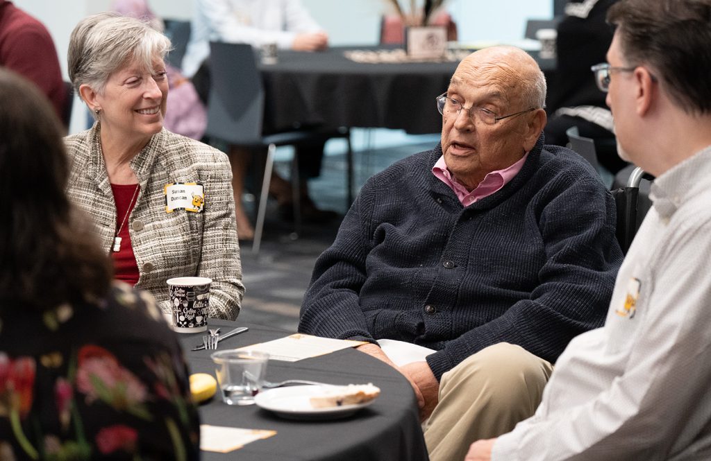Bill Bondeson sitting and speaking to a group of individuals.