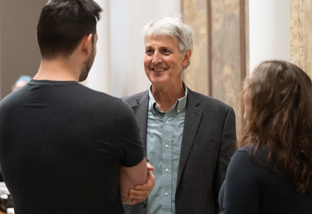 David Schenker smiling while talking to two former students.