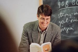 David Schenker smiling while reading a book.