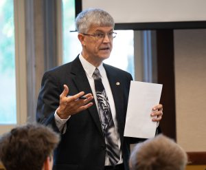 Jim Spain standing while talking with other individuals.