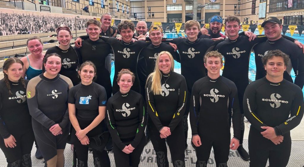 A group of students smiling while wearing scuba gear and posing for a photo.