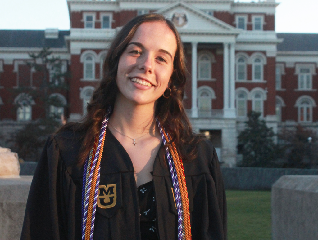 Emma Morrow posing for a graduate photo in front of Jesse Hall.