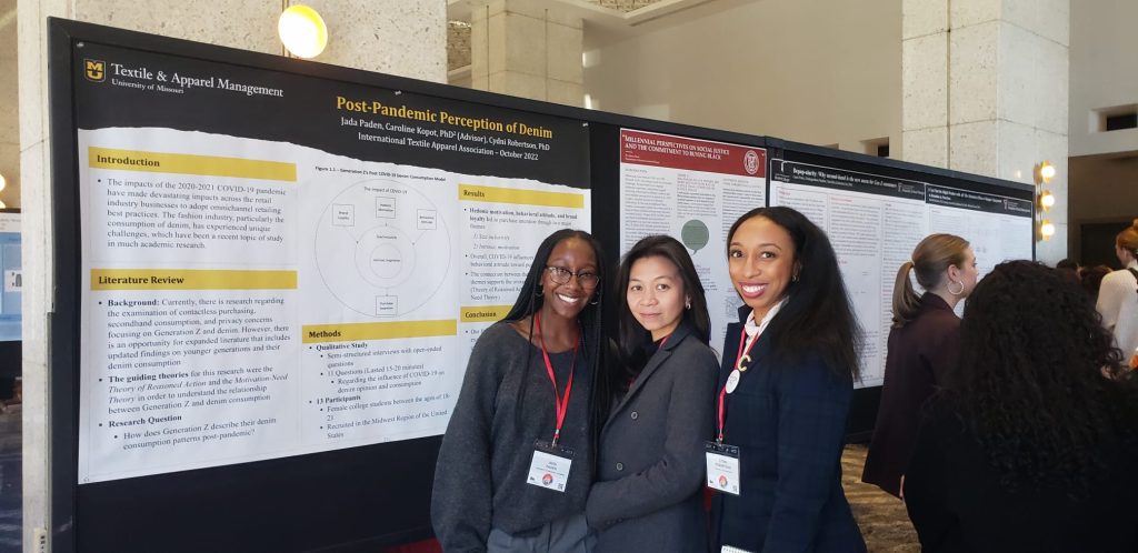 3 women standing in front of a research presentation poster, smiling at the camera