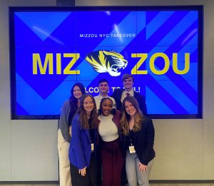 Students pose for a picture in front of an electronic screen that says Mizzou.