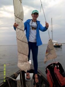 Molly McDermott holding onto mast of sailboat